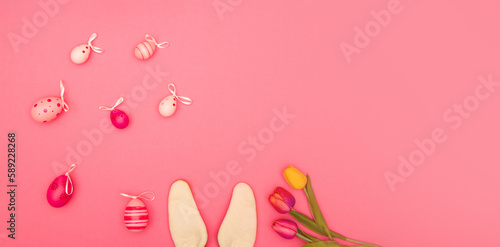 Pink background with Easter eggs, bunny ears and flowers offers plenty of room for copying