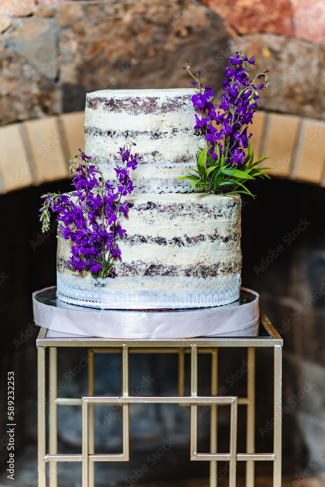 Vertical shot of tasty birthday cake decorated with lavender flower in banquet hall in front of the fireplace