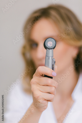 Woman doctor holding dermatoscope equipment for skin examination photo