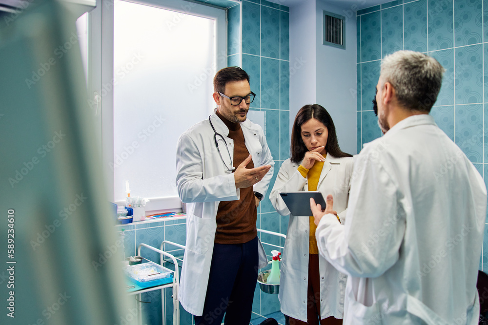 A thoughtful female doctor holding a tablet and standing with her male colleague. A thoughtful female doctor holding a tablet and standing with her male colleague.