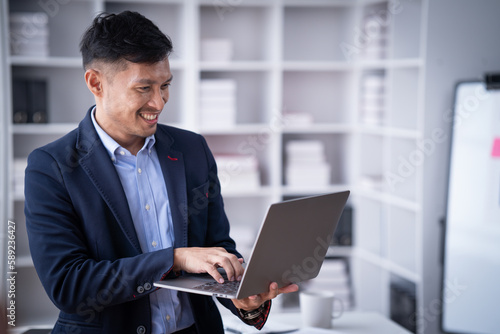 Portrait of Smiling young male employee feel euphoric with promotion offer in paperwork letter in office. a cheerful man sitting at his desk using smart phone at home office.
