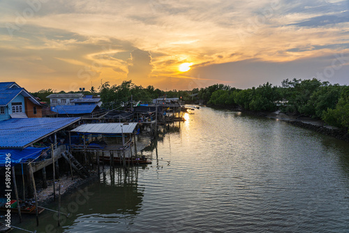 Many fishing community houses have fishing boats moored next to the river that leaves estuary of the Gulf of Thailand in the evening.
