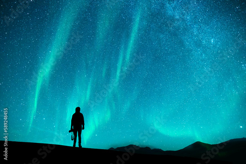 Fantasy landscape,  silhouette of a hiker standing on the starry sky with Aurora lights .