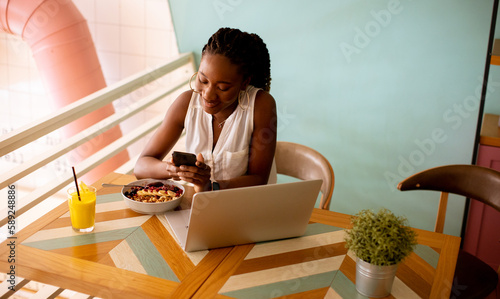 Young black woman using mobile phone in the cafe