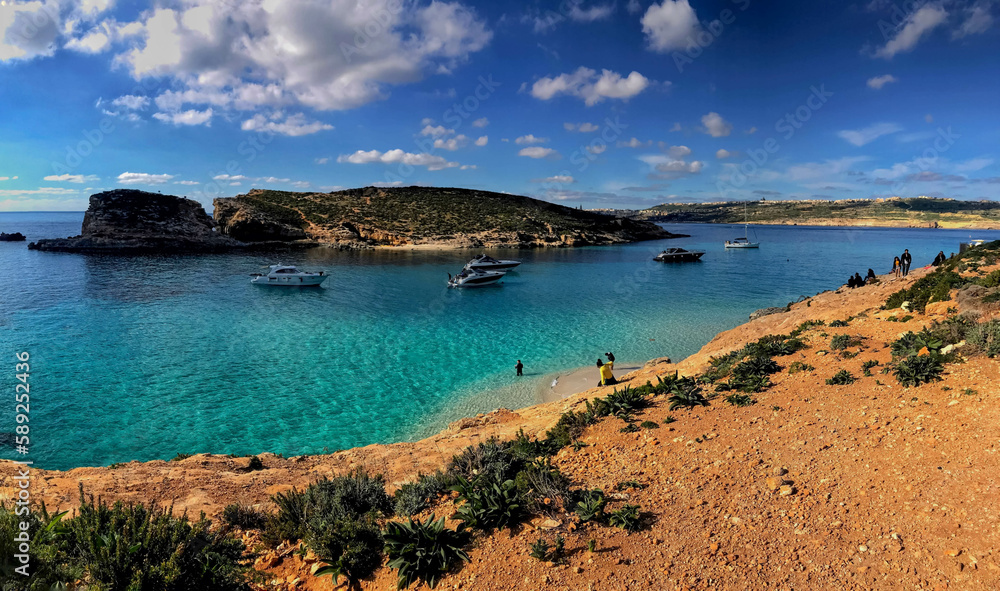 Beautiful beach with crystal blue waters, with people bathing. Boats and boats strolling through the waters of the island of comino in malta.