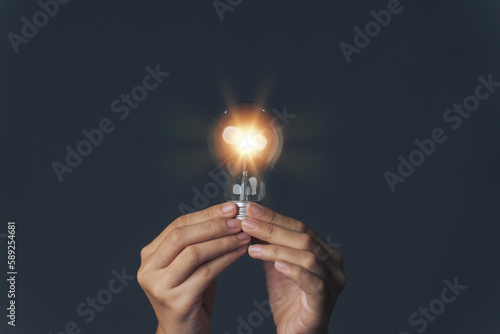 The hand is holding a light bulb that lights up. The concept of finding new ideas for friends to develop ideas education and business