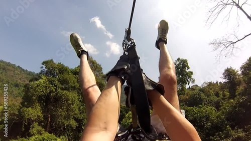 Guy extreme jumping on a zipline, gibbon experience. Tourist in the wild jungle of thailand photo