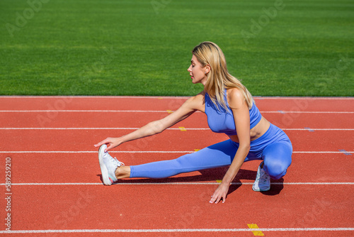 Female runner stretching before workout. Sports exercises and stretching in the stadium. Physical training girl. Fit girl do outward lunging. Physical training education. Sports lesson