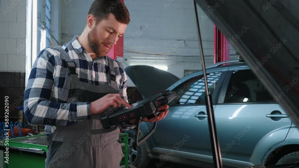 With tablet in hands. Man is repairing the car at a service station. With tablet in hands. Man is repairing the car at a service station.