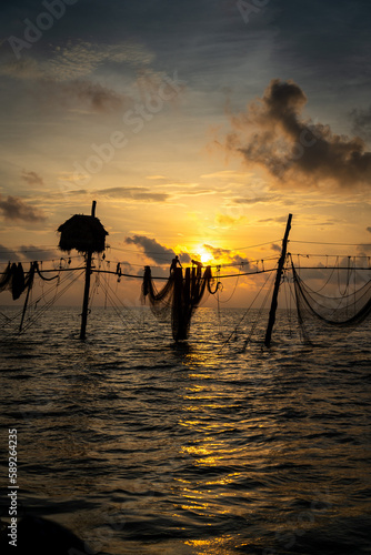 Silhouette of fishermen pulling a nets on fishing poles at sea in Tra Vinh province, Vietnam, Asia during sunrise, local people call it is Day hang khoi.