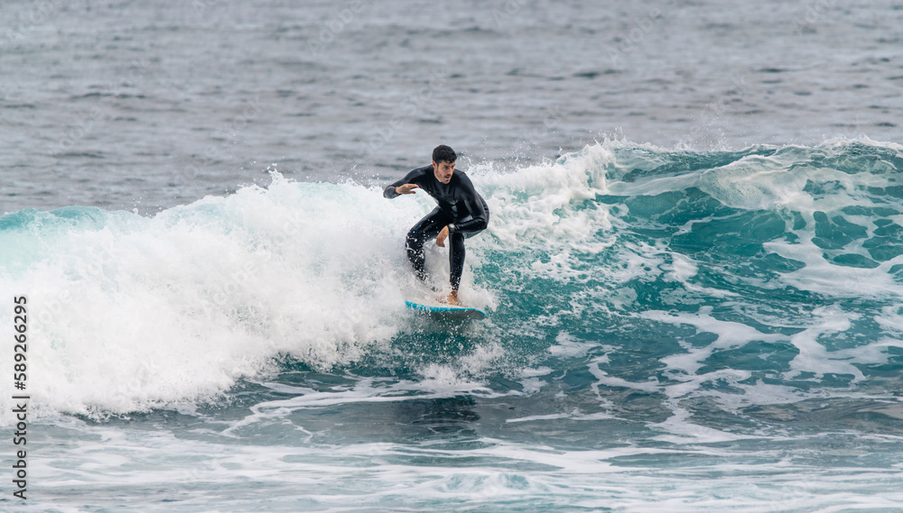 Young man surfing a wave in a wetsuit in Tenerife Young man surfing a wave in a wetsuit in Tenerife