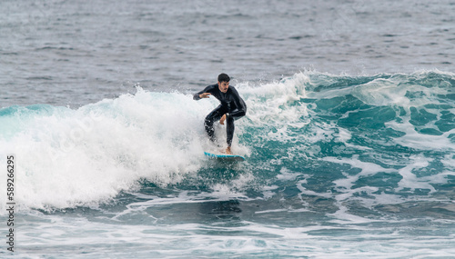 Canvas Print Young man surfing a wave in a wetsuit in Tenerife