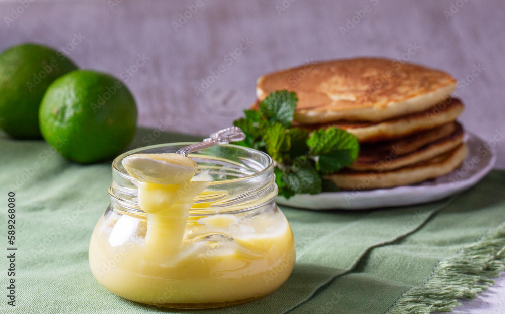 Custard lime curd served with pancakes on a light background. Rustic style.