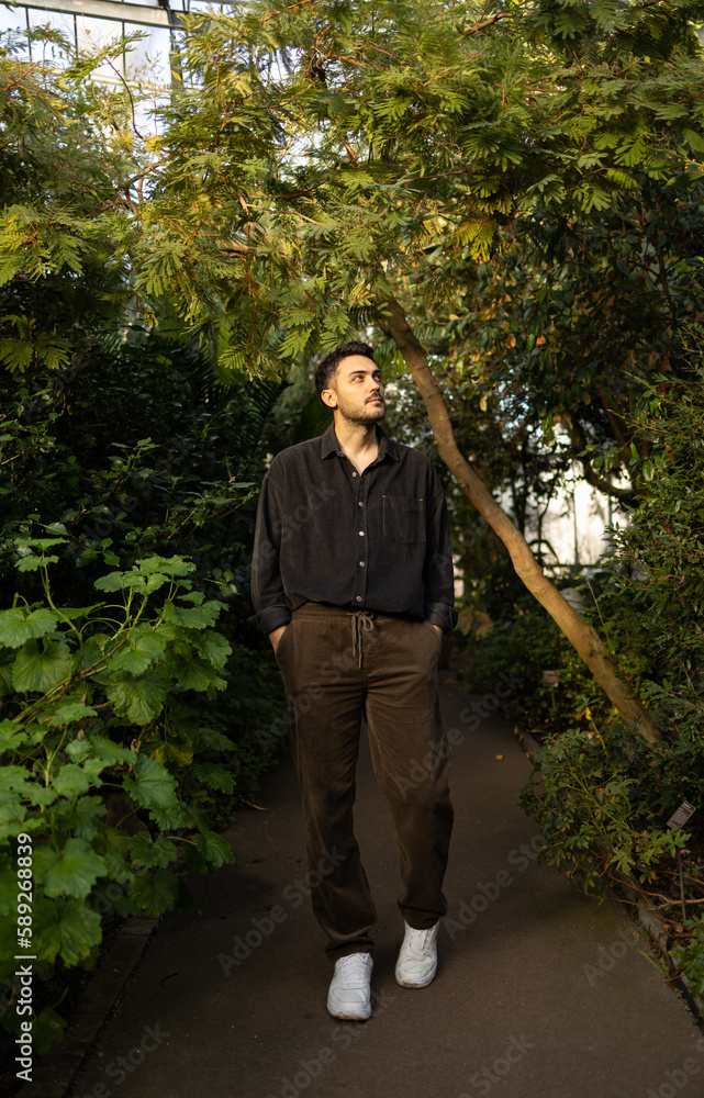 Young man is standing in front of different kind of trees. Young man is standing in front of different kind of trees.