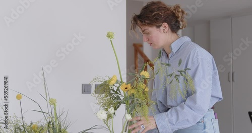 female doing new bouquet. Girl working in flower shop studio. Female florist artist cleans flowers for a beautiful bouquet, workplace view. High quality 4k footage