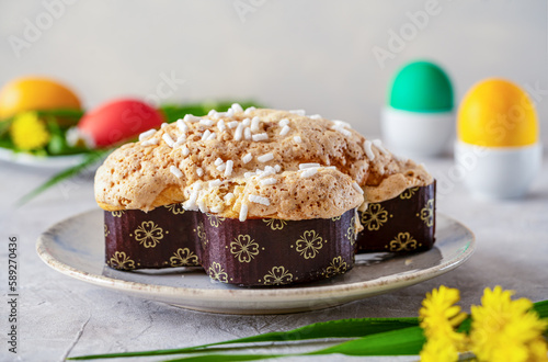 Italian Easter cake Colomba on plate with collared eggs and wild flowers