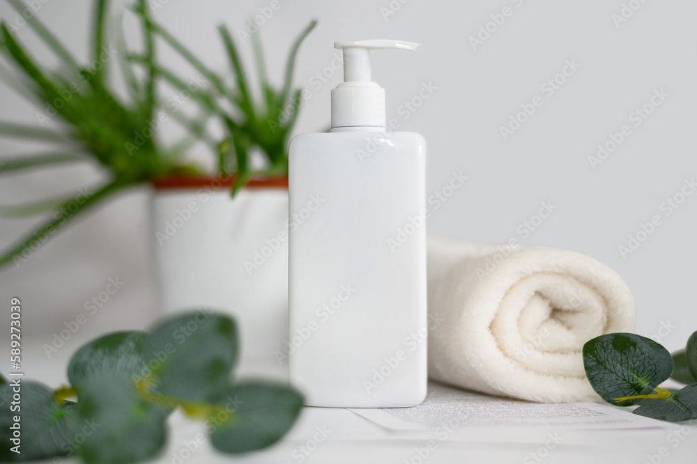 White hand cleaner with white towel and eucalyptus branches. On a gray background. White hand cleaner with white towel and eucalyptus branches. On a gray background.