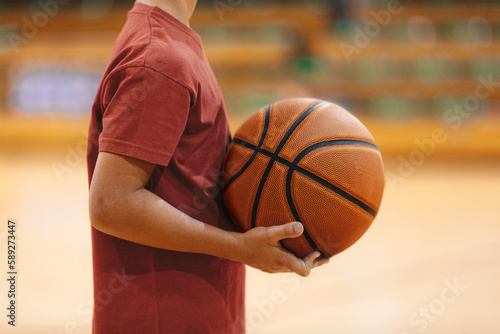 Young School Boy Holding Basketball Ball in Hands at Training Game. Junior Basketball Players on a Game. Male Elementary School Basketball Team Playing Game. © matimix