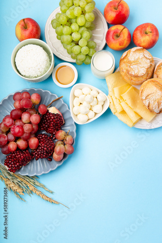 Fototapeta Naklejka Na Ścianę i Meble -  Jewish Shavuot Holiday Card. Dairy Products, Grapes, Cheese, Bread, Milk on Blue Background.