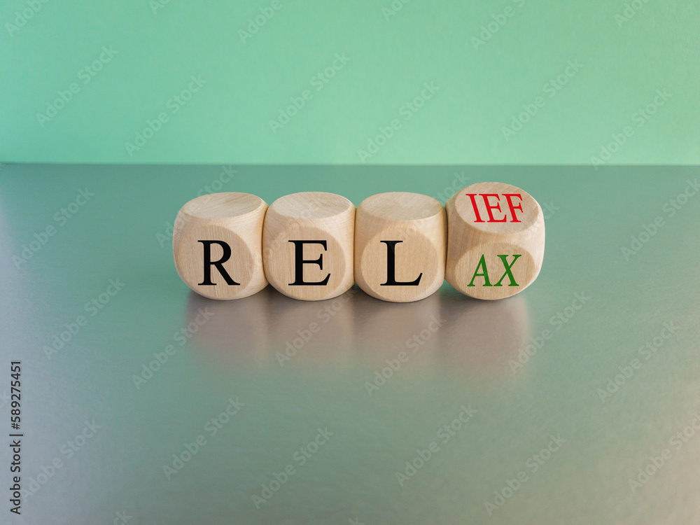 Relief and relax symbol. Turned cubes and changes the word Relief to Relax. Beautiful blue background, grey table. Business and Relief and relax concept. Copy space Relief and relax symbol. Turned cubes and changes the word Relief to Relax. Beautiful blue background, grey table. Business and Relief and relax concept. Copy space