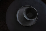 Black round dishes on a round black table.
