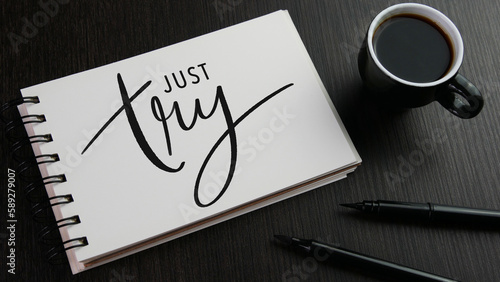 Tablou pe pânză JUST TRY black hand lettering in notebook with cup of espresso and pens on black