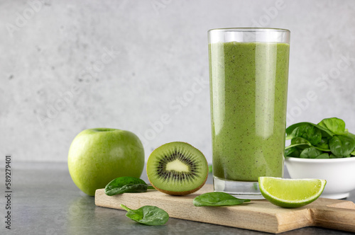 Green detox smoothie on gray background. Green smoothie with spinach, kiwi, banana, apple. Copy space.