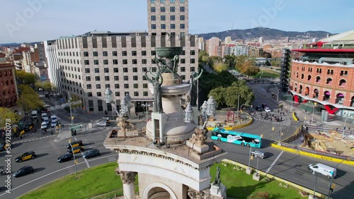 Aerial view of Font monumental and Arenas de Barcelona Plaza de Espana of Squares is one of Barcelona most important squares. Cars driving around monumental fountain and people crossing road. 4K video photo