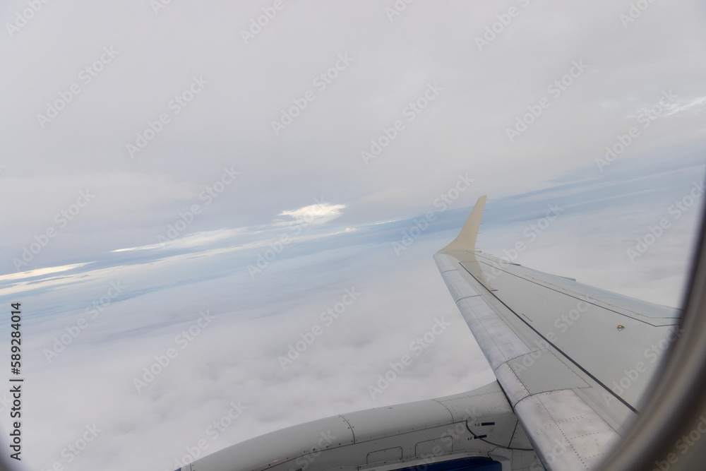 view of jet plane wing on the background of thick clouds and blue sky