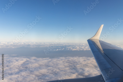 view of jet plane wing on the background of thick clouds and blue sky
