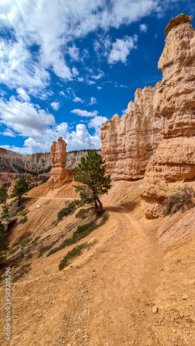 Man with backpack looking at scenic aerial view of hoodoo sandstone rock formations on Peekaboo hiking trail in Bryce Canyon National Park, Utah, USA. Natural amphitheatre on sunny summer day