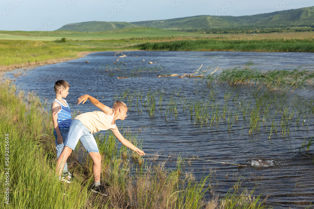 Hobby and leisure activities during summer holidays. Little Caucasian boys brothers at fishing during the summer holidays