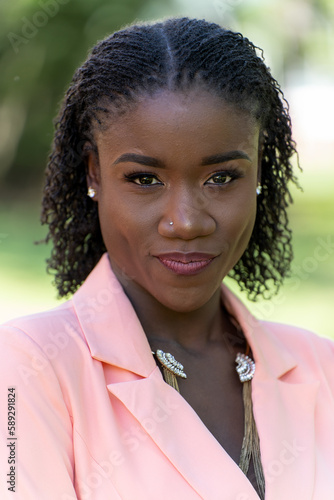 Closeup outdoor portrait of a beautiful young black woman with a sister loc hairstyle wearing a blazer dress smiling