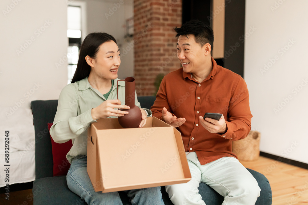 Positive asian husband and wife new owners renters of apartment unpacking after relocation moving Positive asian husband and wife new owners renters of apartment unpacking after relocation moving