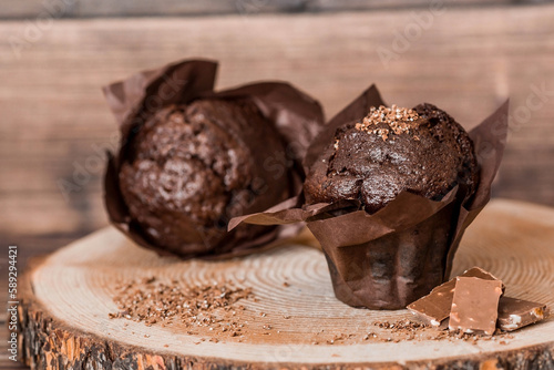 Delicious freshly baked chocolate muffins on a wooden background. Delicious cupcake close-up. The context of a bakery with pastries. Confectionery products.