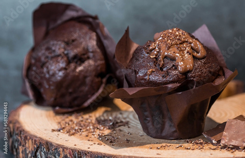 Delicious freshly baked chocolate muffins on a dark background. Delicious cupcake close-up. The context of a bakery with pastries. Confectionery products.