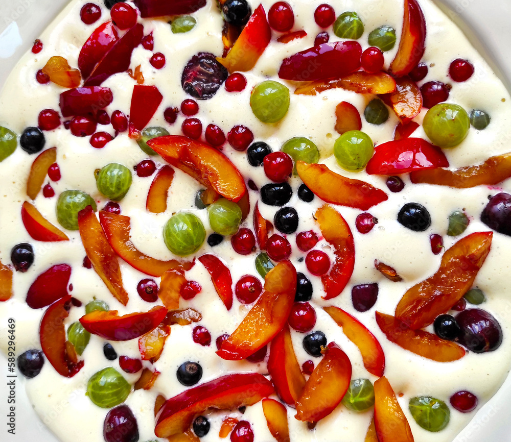 Plate of uncooked clafouti with berries and fruits. Close-up view from above. Homemade berry clafoutis pie