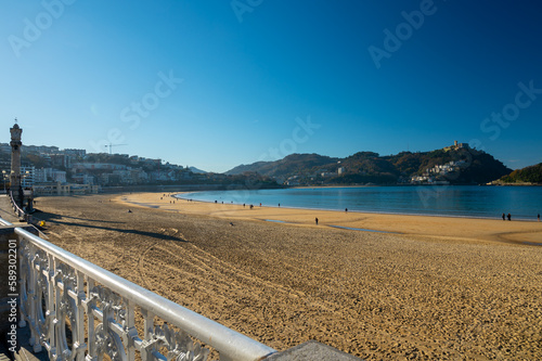 Walking on promenade along white sandy La Concha beach in central part of Donostia or San Sebastian city, Basque Country, Spain