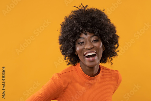 Beauty young woman in orange golf on isolated yellow background.