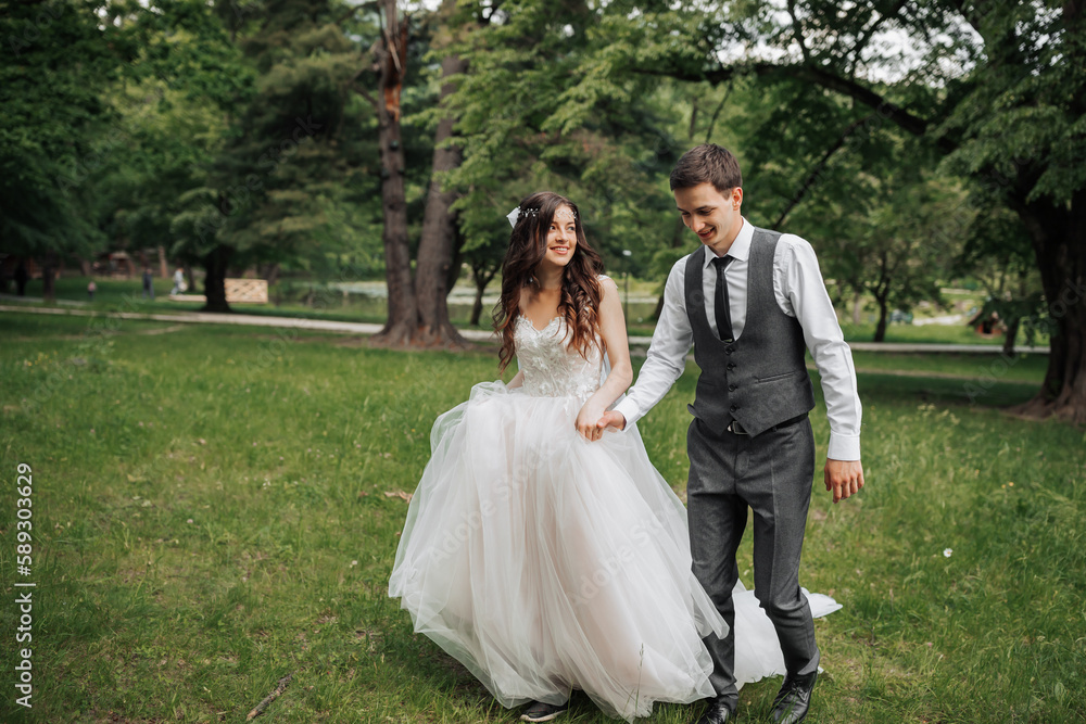 Stylish young brides, happy on their day, enjoy each other. They are walking in the spring park. Spring wedding. Natural makeup