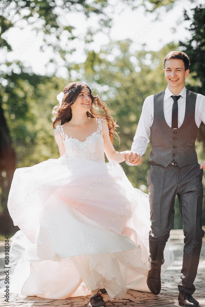 Groom and bride in the garden. Spring wedding in the park. Happy wedding couple running in the park. Stylish and beautiful. Princess dress.