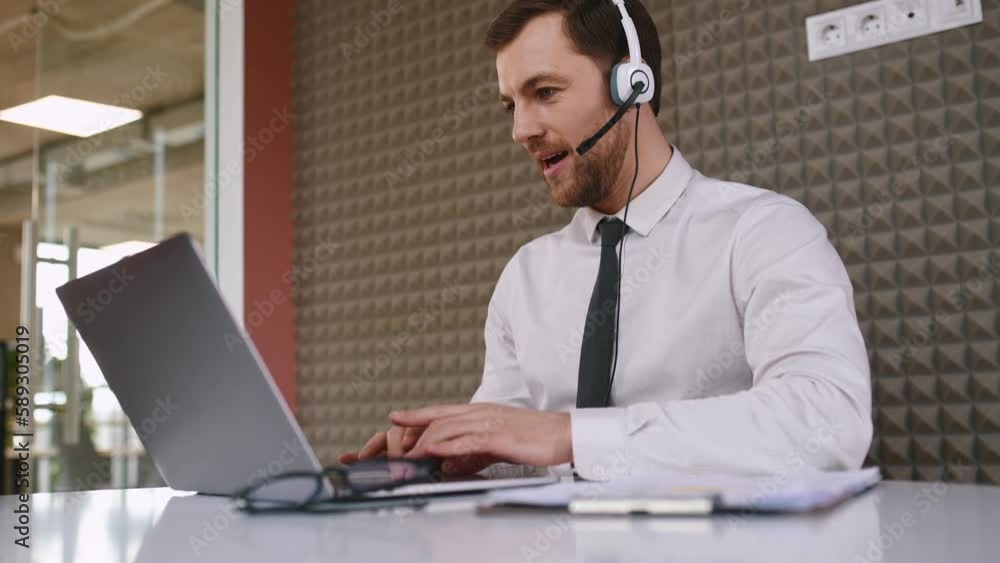 Office worker is sitting by a laptop and having online conference. Talking, giving advice. Office worker is sitting by a laptop and having online conference. Talking, giving advice.