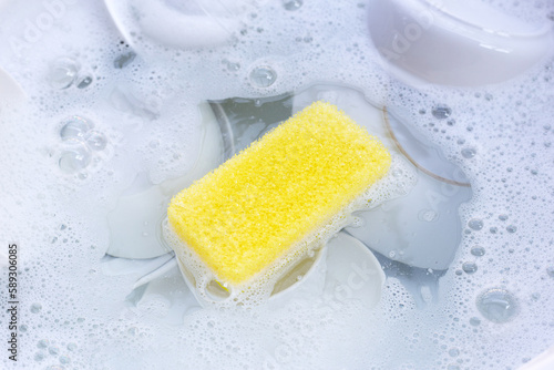 Fotografie Dishes and bowls in water and bubbles of dishwashing liquid