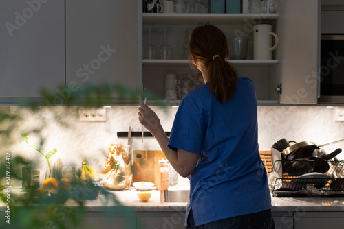 Rear view of nurse removing glassware from cabinet in kitchen at home photo