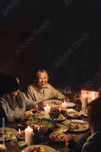 Happy senior woman with friends enjoying having food at dinner party