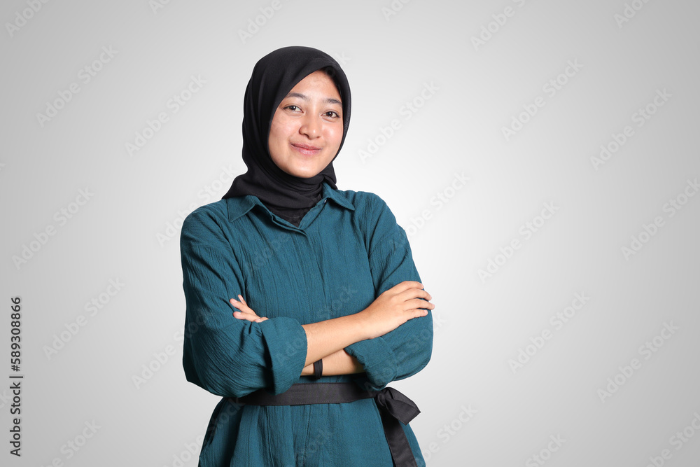 Portrait of cheerful Asian muslim woman with hijab, keeping arms crossed and smiling looking at camera. Isolated image on white background Portrait of cheerful Asian muslim woman with hijab, keeping arms crossed and smiling looking at camera. Isolated image on white background