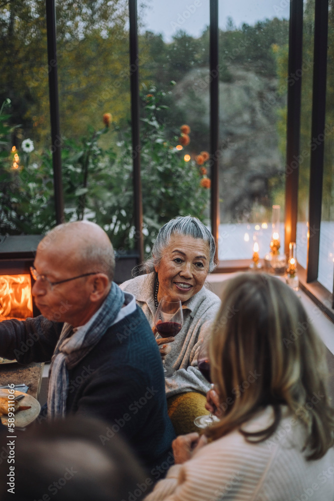 Senior female friends talking to each other during dinner party Senior female friends talking to each other during dinner party