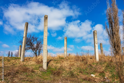 High iron concrete pillars in nature on a sunny day. Abandoned construction site. Unfinished house or other architectural structure