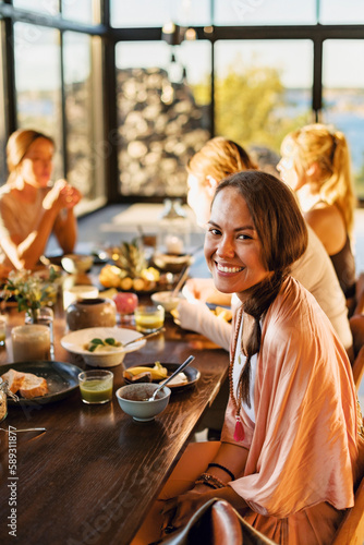 Portrait of happy woman sitting with breakfast on dining table at retreat center photo