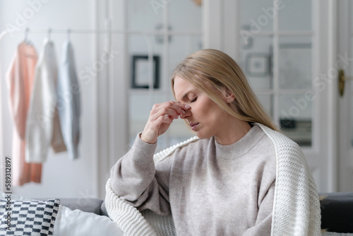 young female suffering from sinus infection, staying sick at home photo